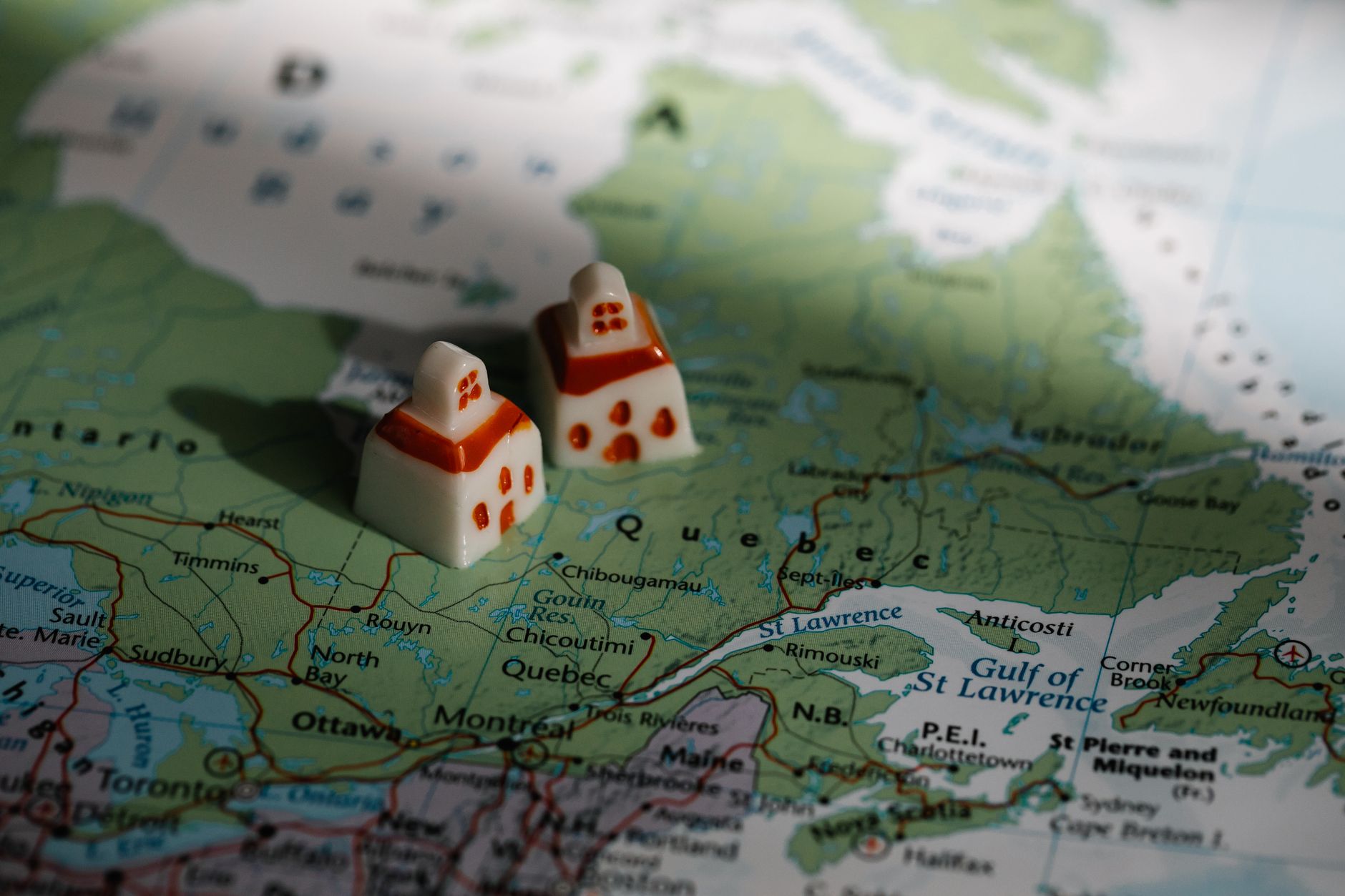 Dwie miniaturowe figurki domów ustawione na mapie Quebecu w Kanadzie