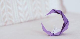 Fioletowy księżyc z eleganckim króliczkiem z origami na jasnym tle