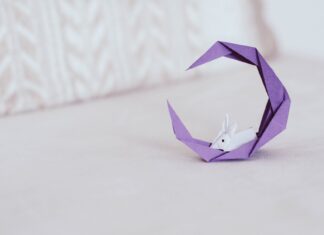 Fioletowy księżyc z eleganckim króliczkiem z origami na jasnym tle