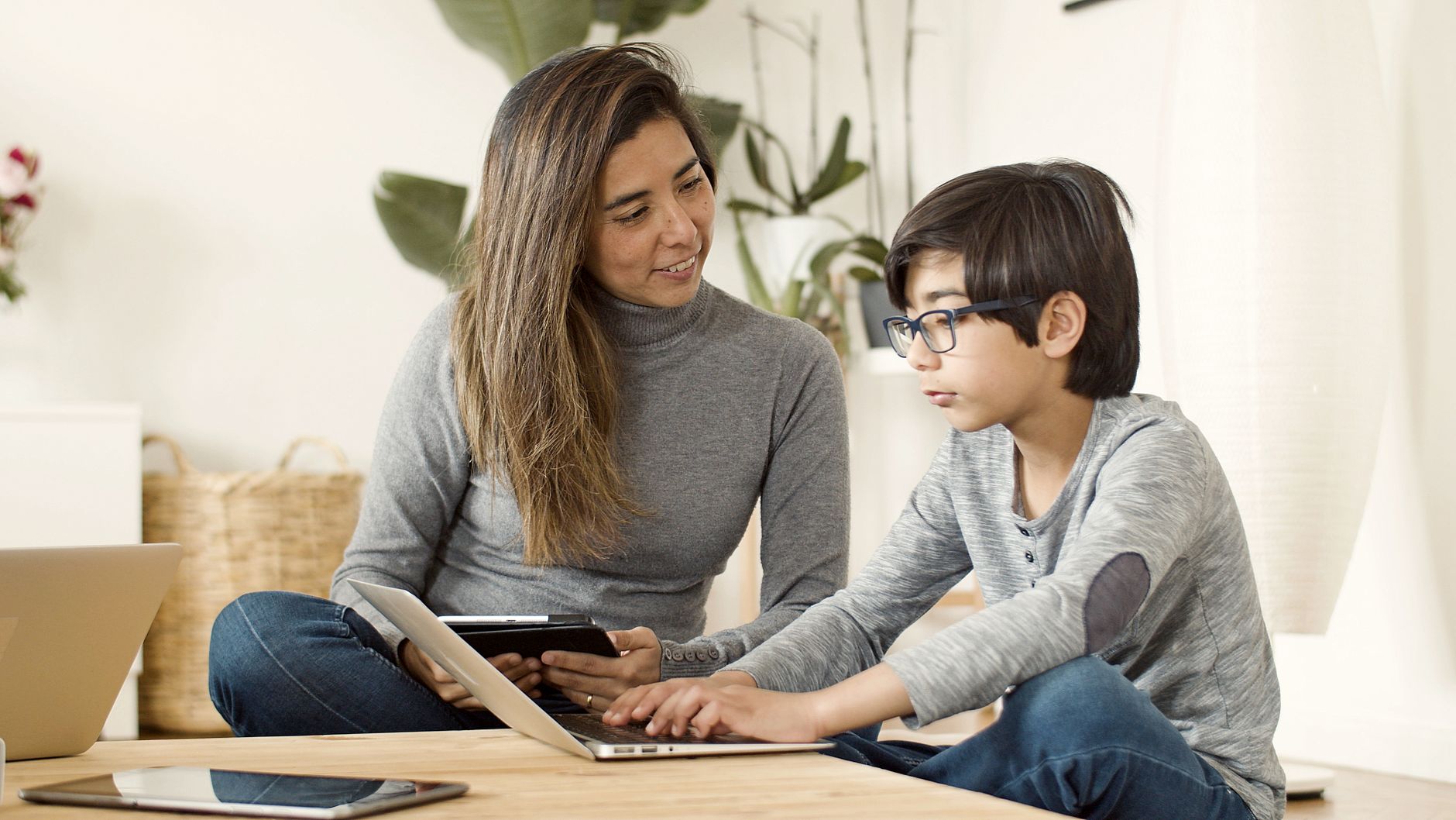 Mama z synem korzystają razem z laptopa i tabletu w salonie