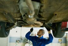 Jakie objawy wskazują na zużyte amortyzatory i kiedy konieczna jest ich wymiana Mechanik ogląda podwozie samochodu w warsztacie samochodowym