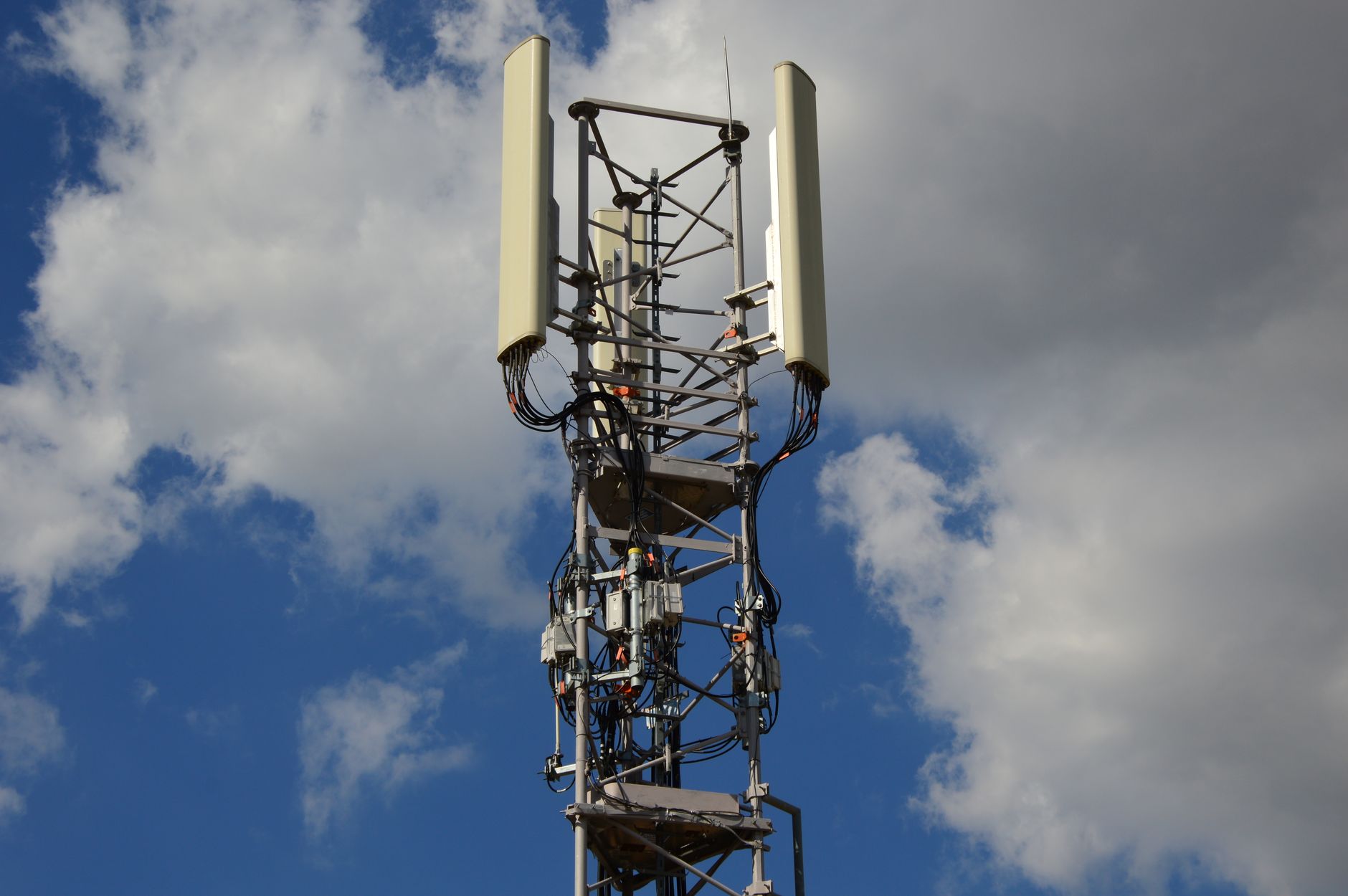 Nowoczesna wieża 5G z antenami na tle nieba z chmurami
