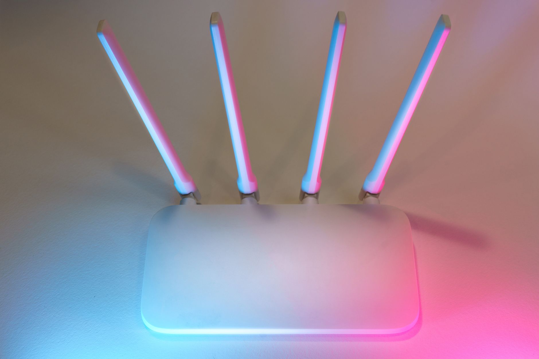 Nowoczesny biały router Wi‑Fi 7 z czterema antenami w kolorowym podświetleniu