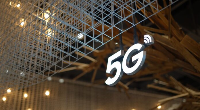 Edge computing i 5G: duet, który zmieni oblicze internetu rzeczy i automatyzacji Podświetlony znak 5G na tle nowoczesnego, geometrycznego sufitu