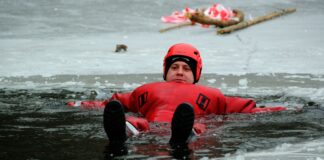 Ratownik w kombinezonie pokazuje techniki ratunku na zamarzniętym jeziorze