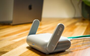 Router Wi‑Fi 6 z antenami na drewnianym biurku w nowoczesnym domu