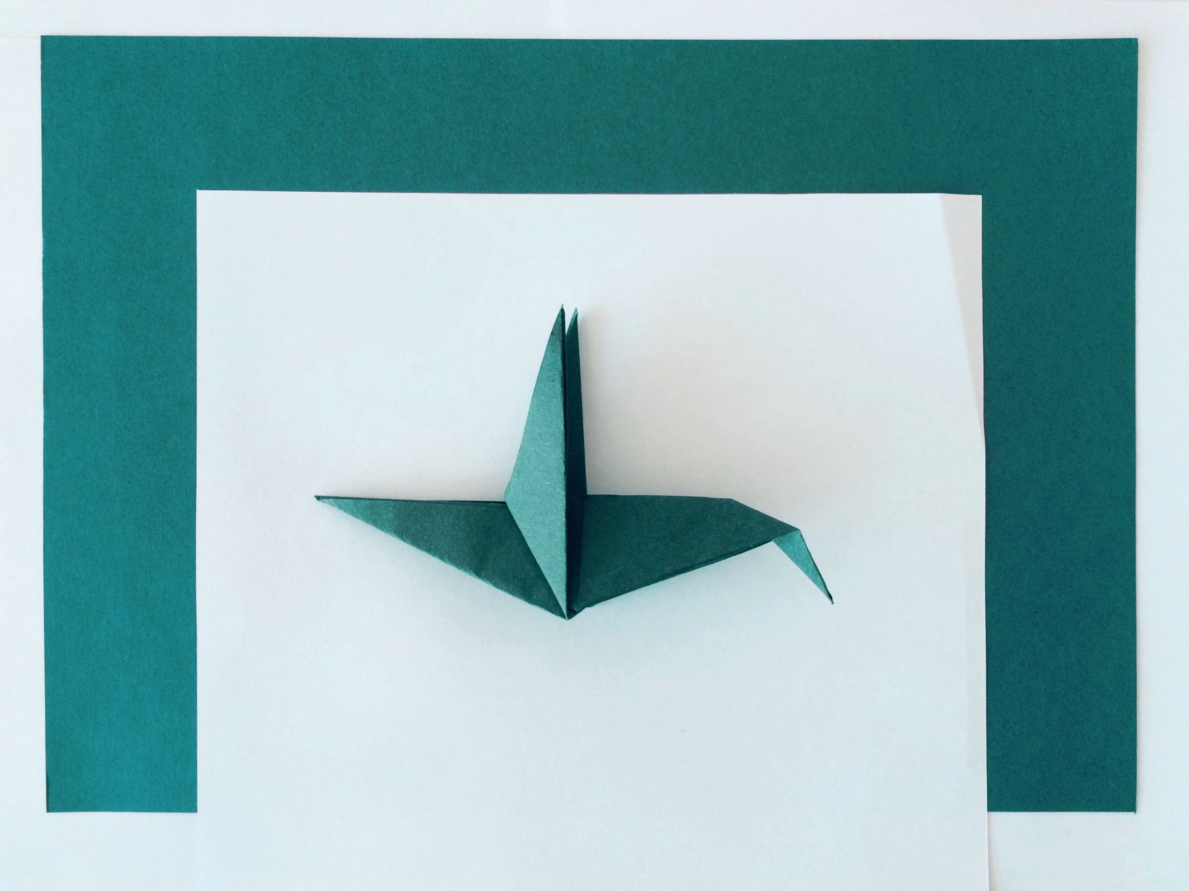 Zbliżenie turkusowego ptaka z origami na białym i turkusowym tle